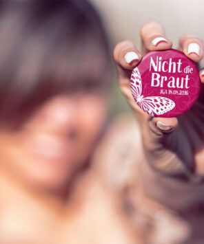 Frau mit JGA Button Nr. 8 in der Hand