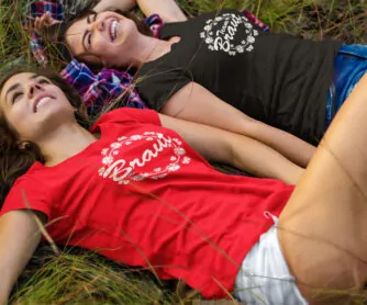 2 Frauen liegen zum JGA lachend im Gras und tragen JGA-Shirts T73